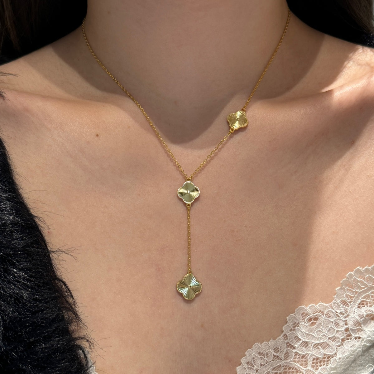 four leaf clover drop Gold necklace with clover pendants on a person wearing a lace top.