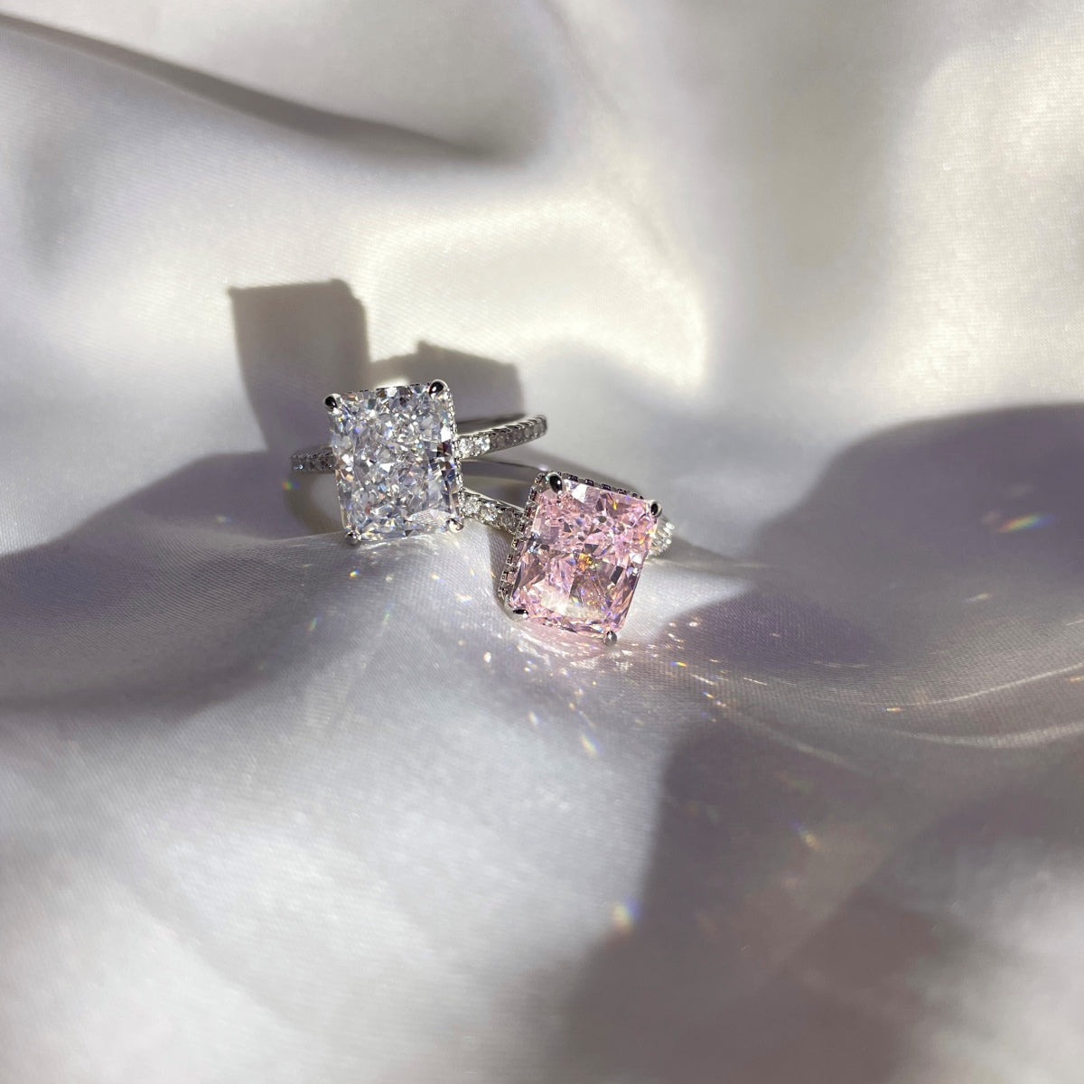 Pair of diamond radiant cut rings on a soft white fabric background