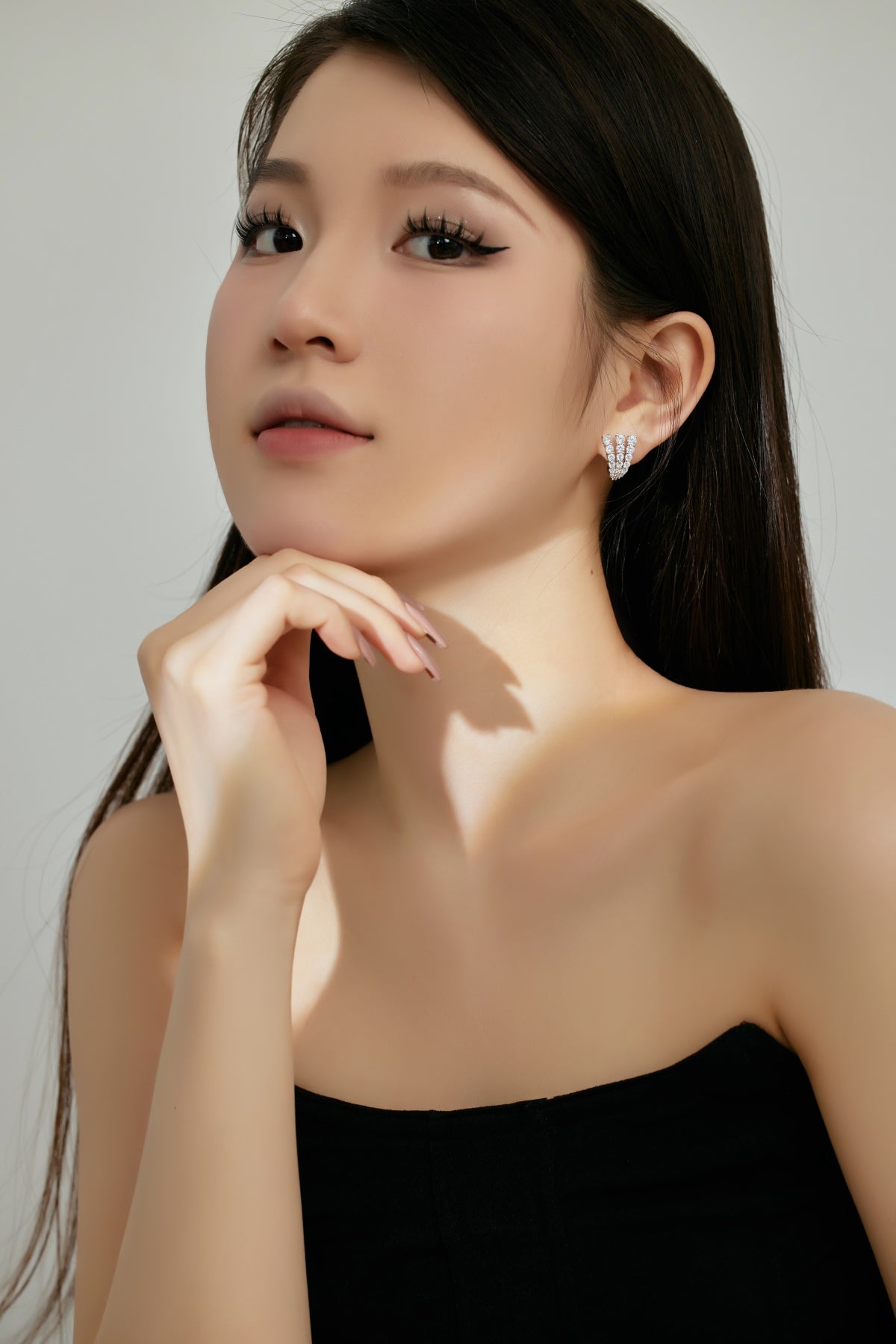 Woman wearing a black strapless top with a plain background