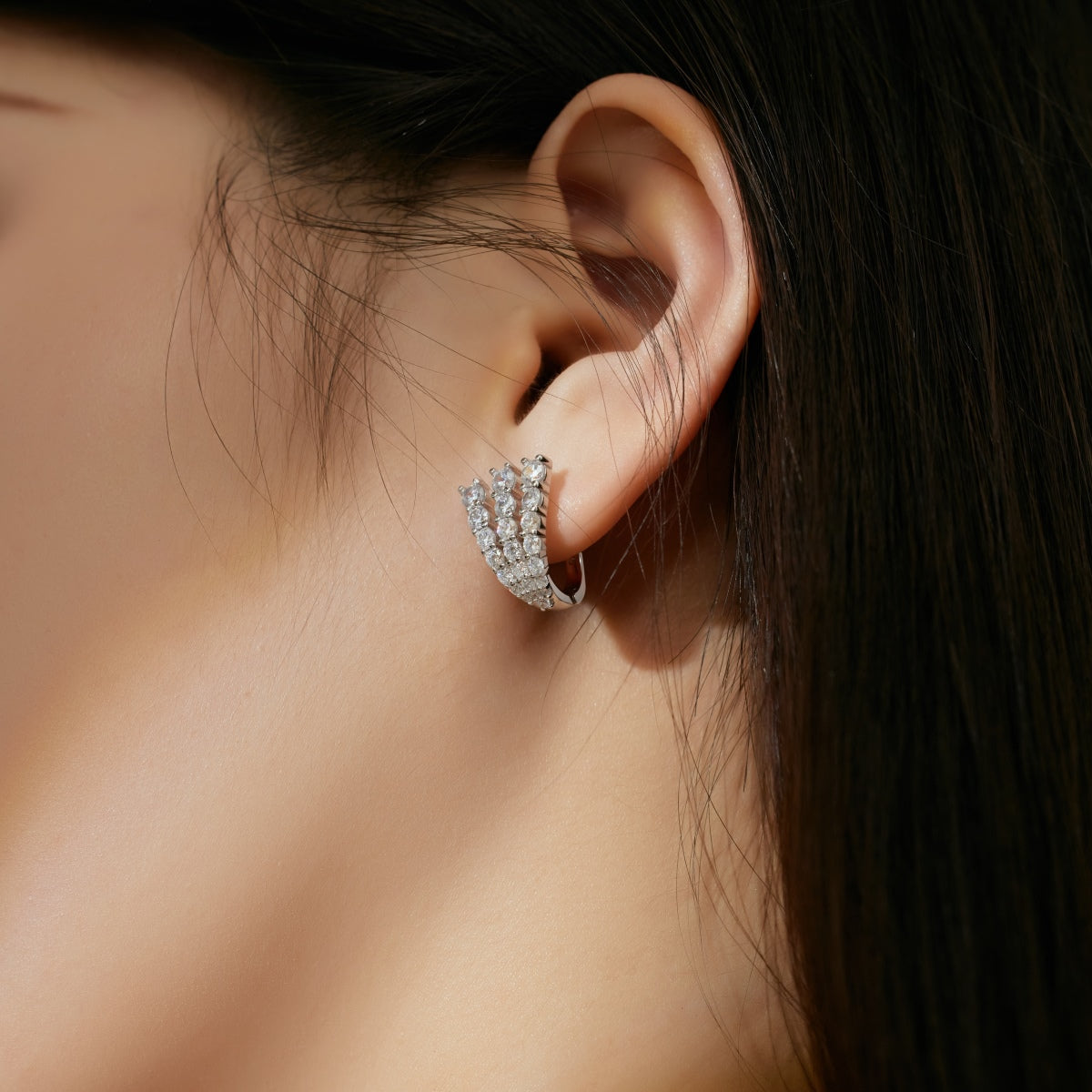 Close-up of a person wearing a silver hoop earring with a blurred background