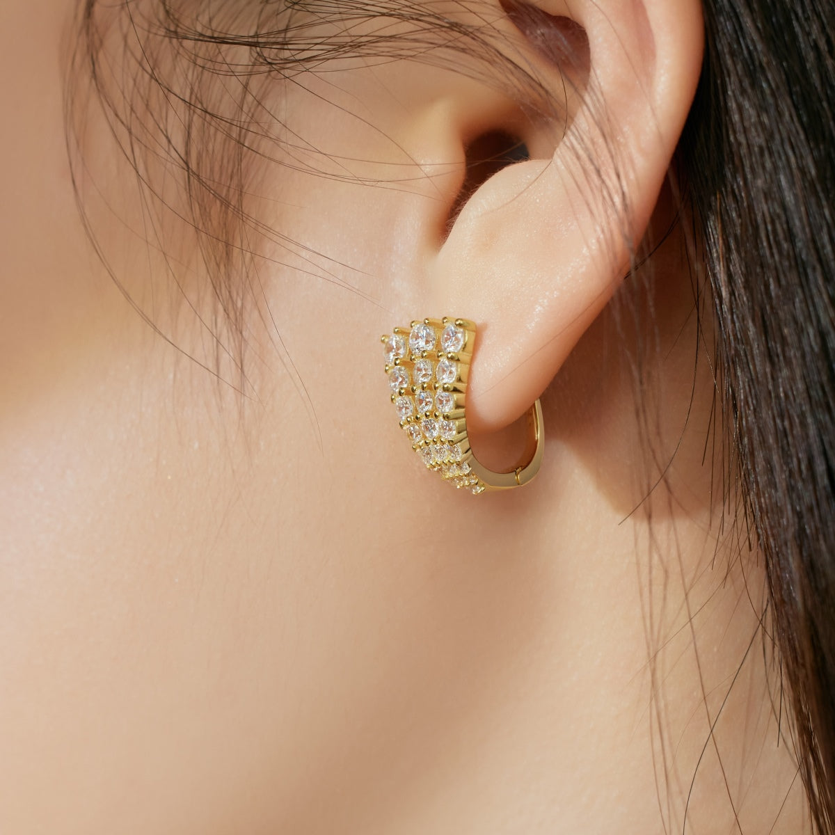 Gold hoop earring with clear stones worn by a person