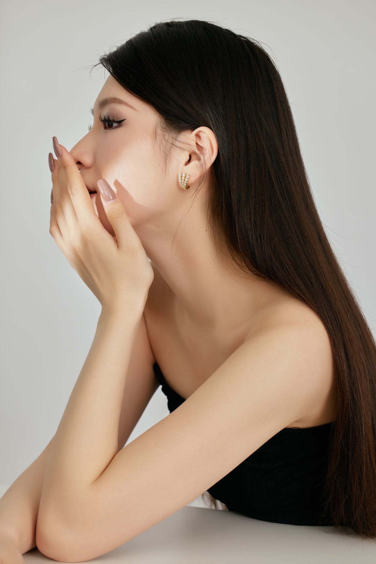 Woman with long dark hair and a black top against a plain background