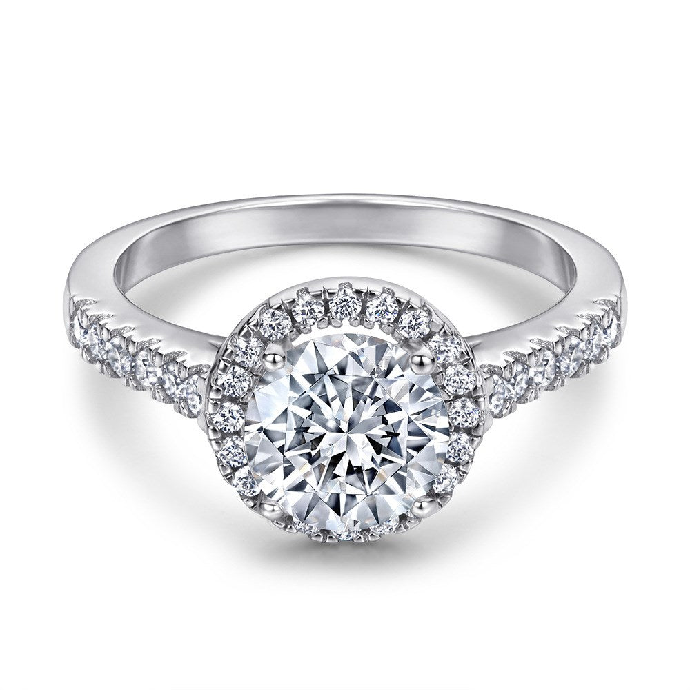 Silver ring with a large central diamond and smaller diamonds around on a white background