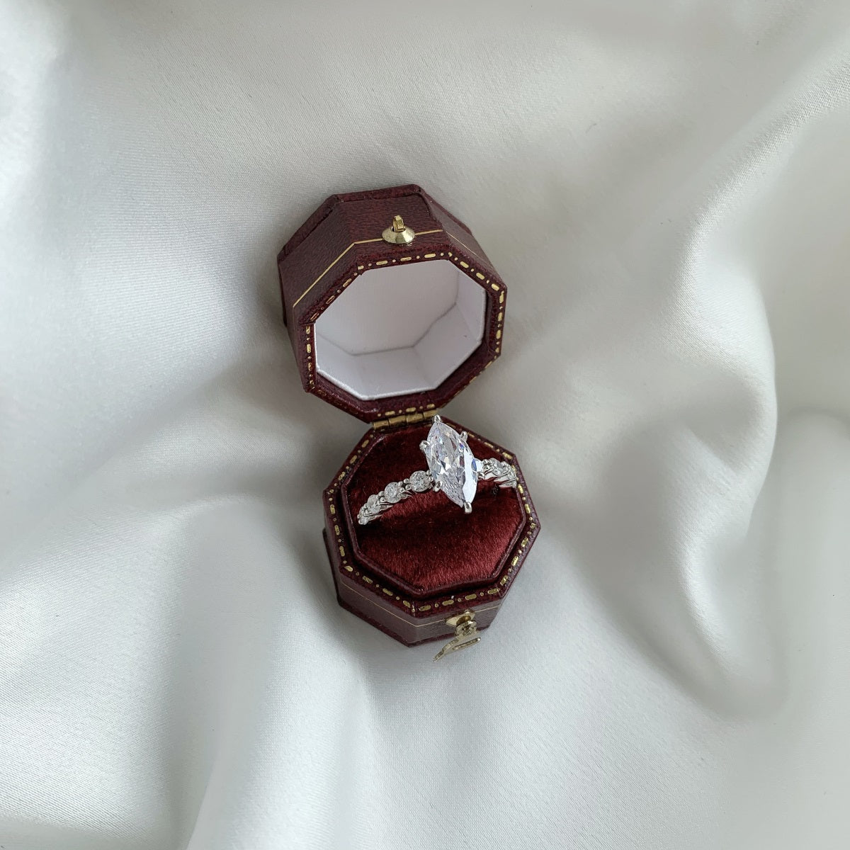 marquise Diamond ring in a hexagonal wooden box on a white fabric background