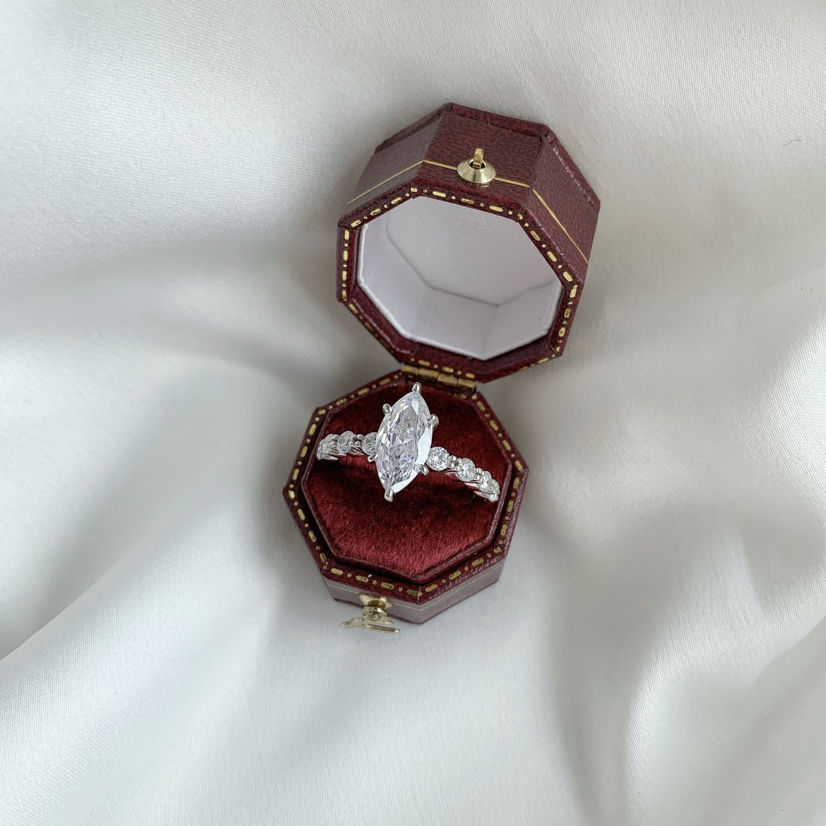 marquise Diamond ring in a hexagonal red velvet box on a white fabric background