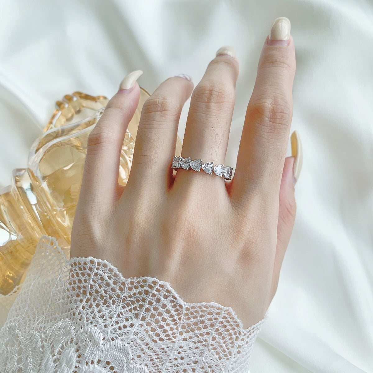 Hand wearing a diamond ring with a soft white background
