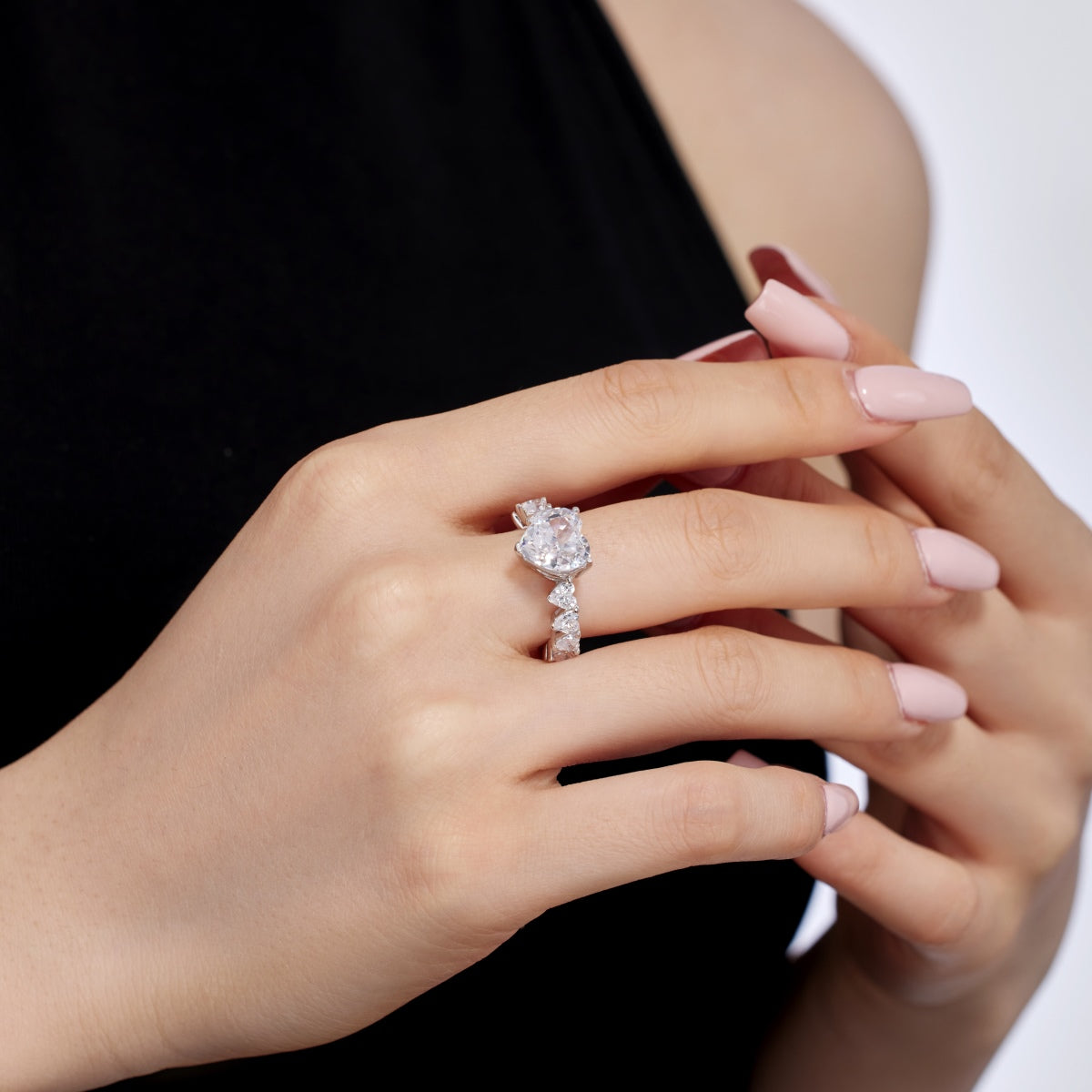 Close-up of a hand wearing a heart diamond ring with a blurred background