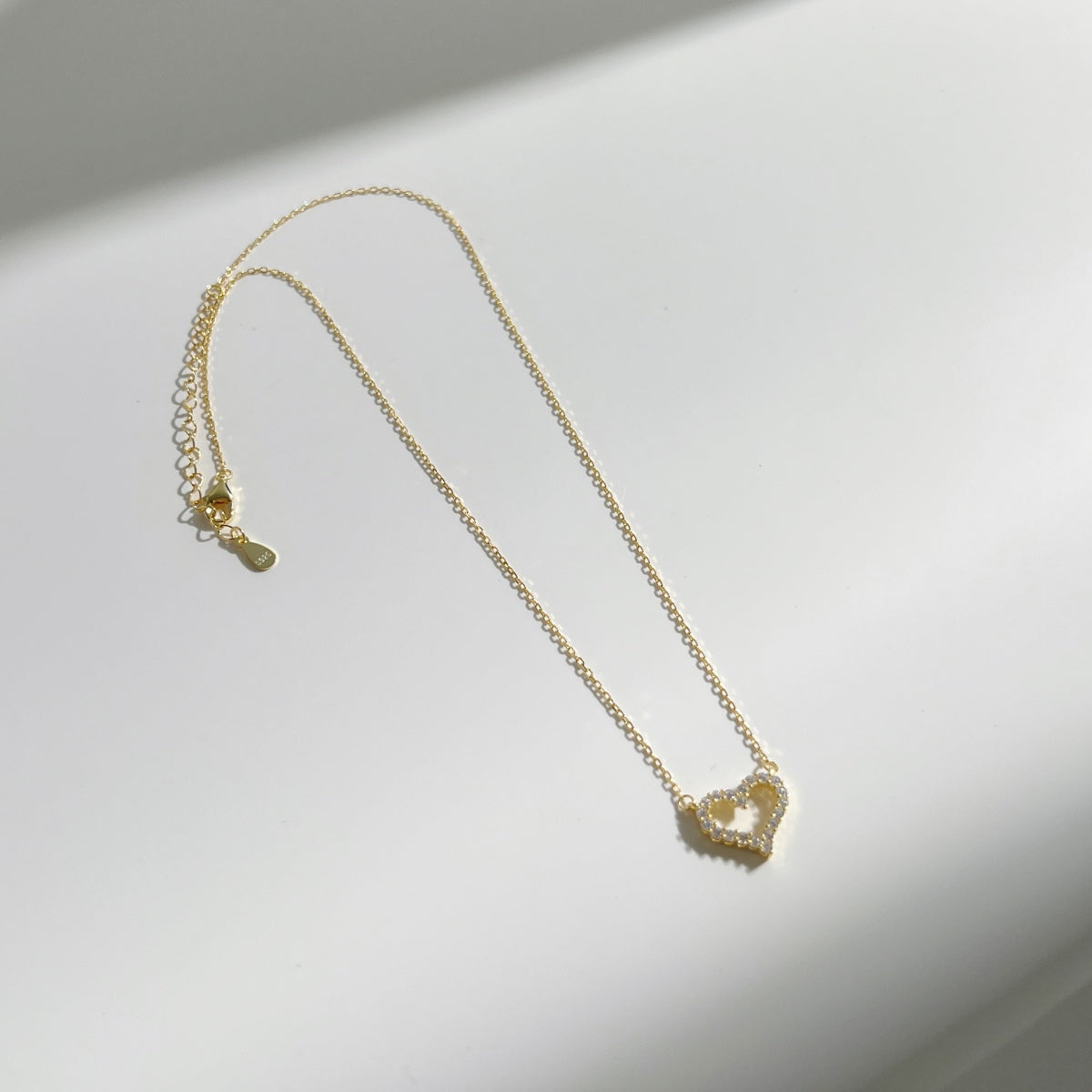 18k gold heart pendant necklace with zircons on a white background