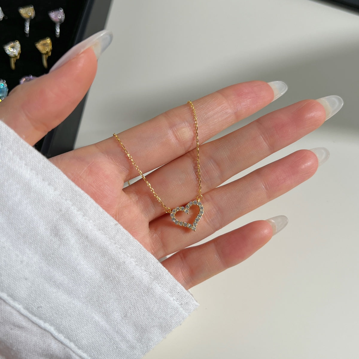 hand showing 18k gold heart pendant necklace with zircons