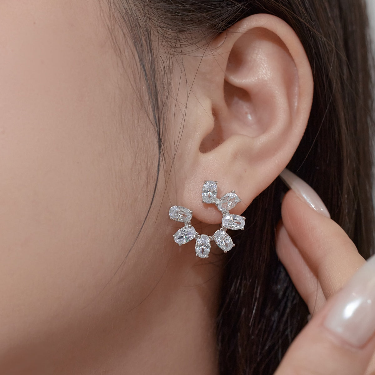 Close-up of a zircon earring being worn on an ear with a blurred background