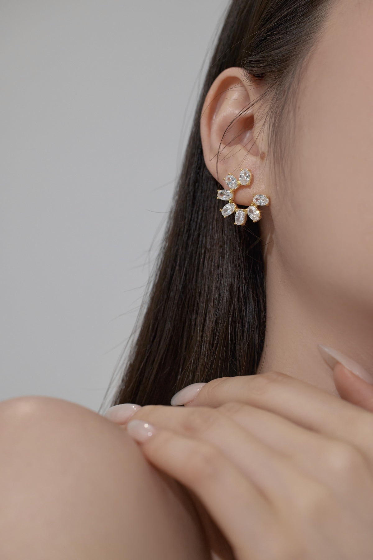 Close-up of a person wearing a floral earring with a neutral background