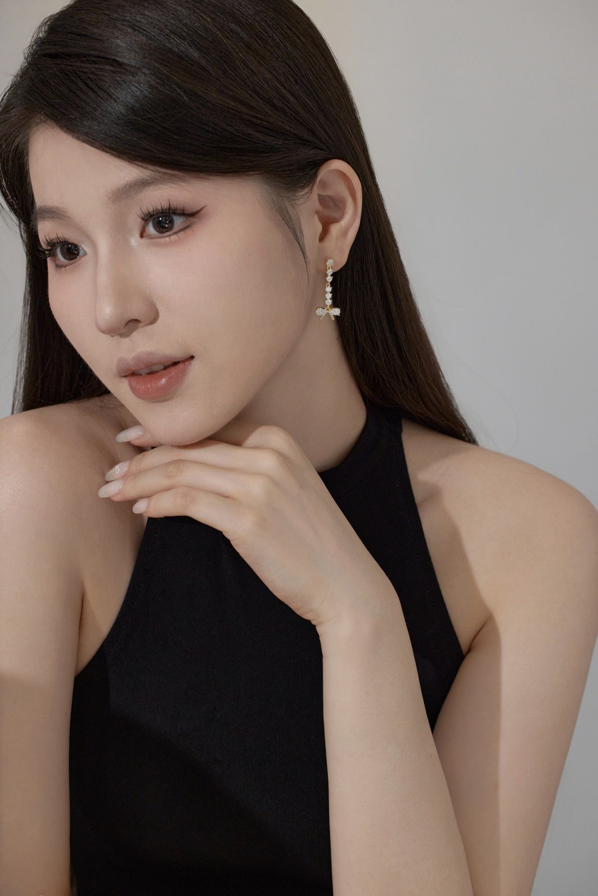 Woman wearing bow shaped drop earrings with a neutral background