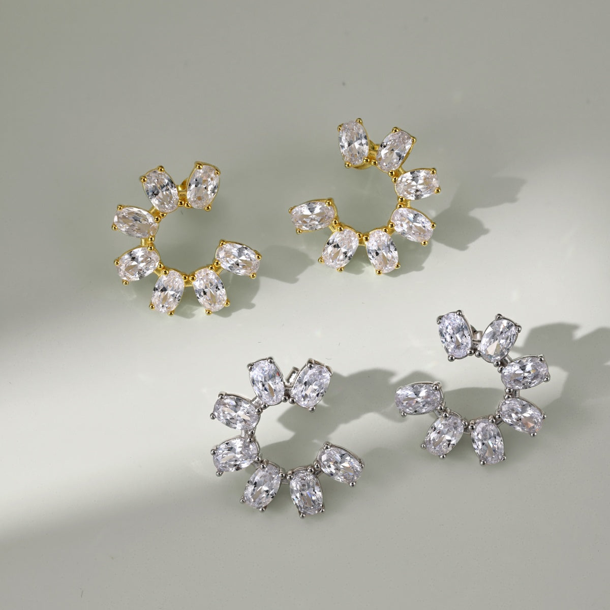 Pair of gold and crystal hoop earrings on a light gray background