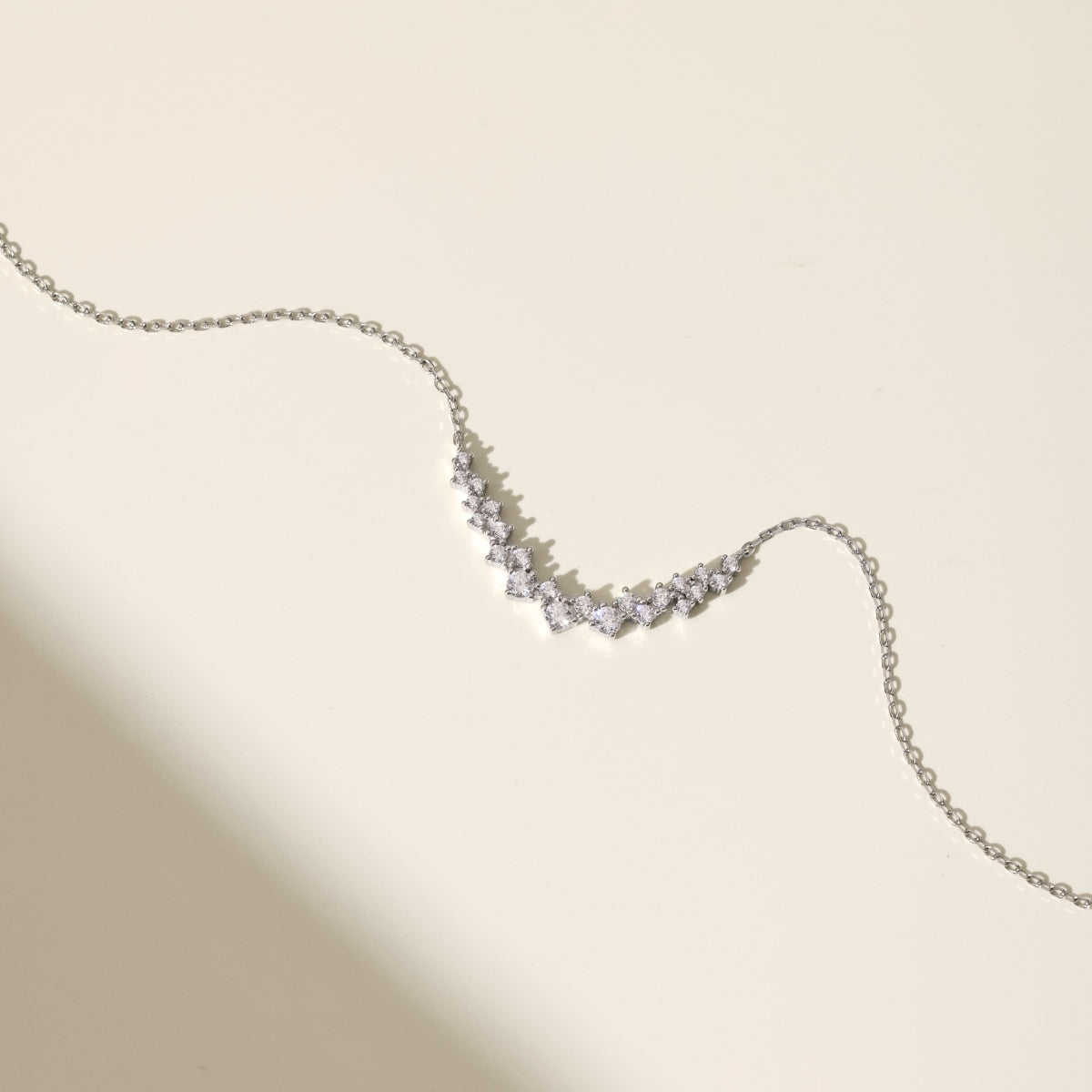 Silver necklace with small diamonds on a beige background