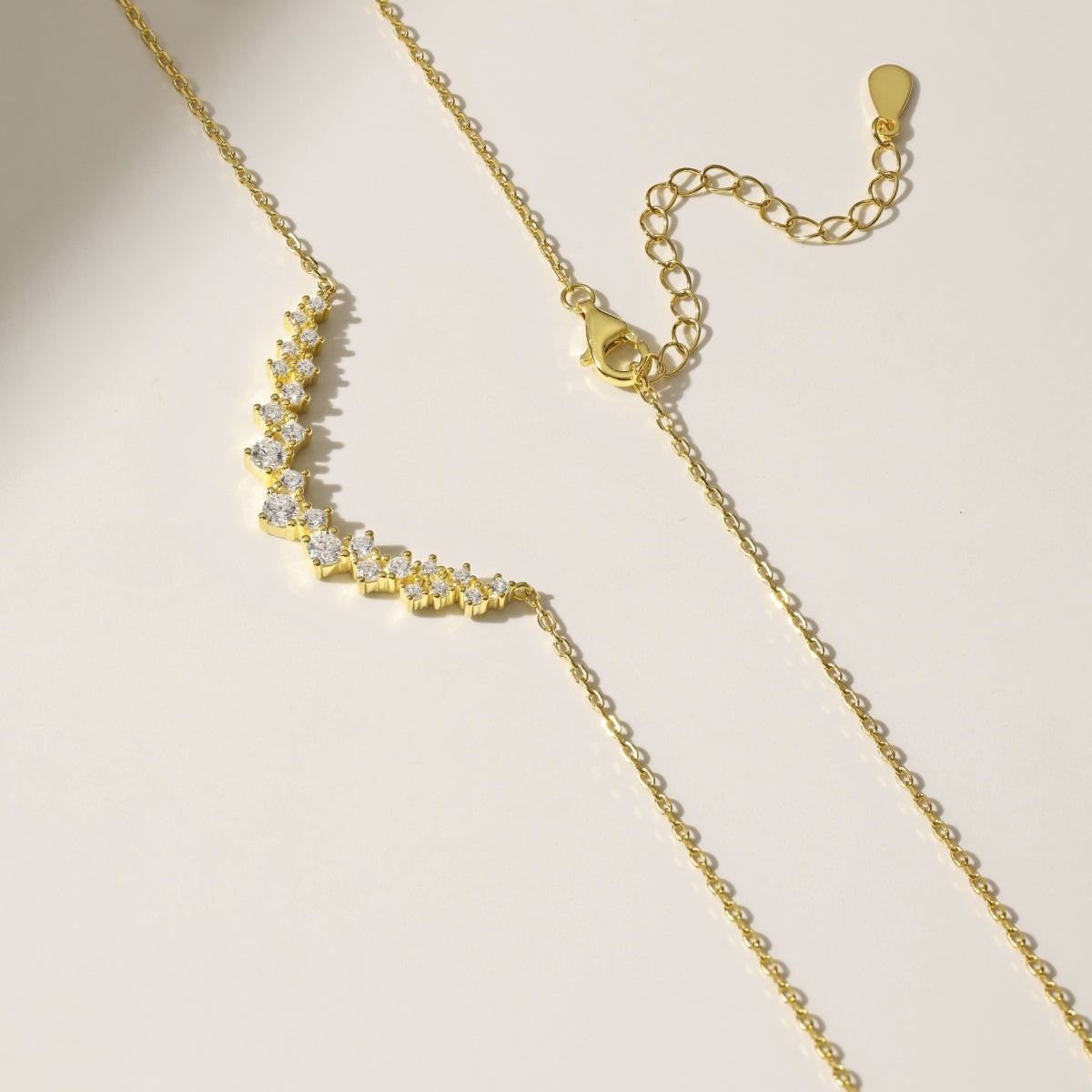 Gold curved pendant necklace with a subtle design on a light beige background