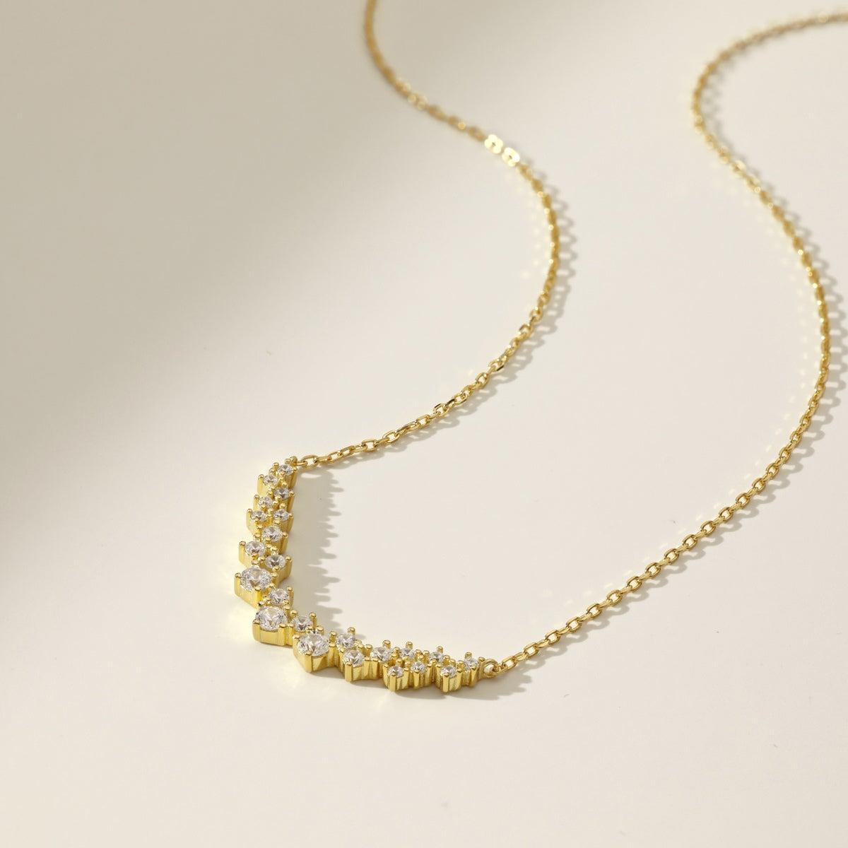 Gold necklace with diamond accents on a beige background