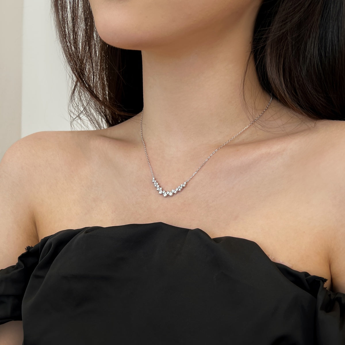 Necklace with small diamonds on a person wearing a black top.
