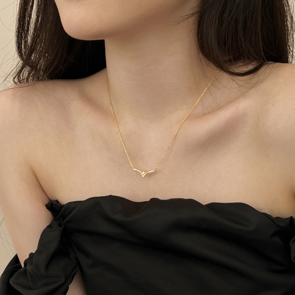 Gold chevron necklace worn by a person with a black top
