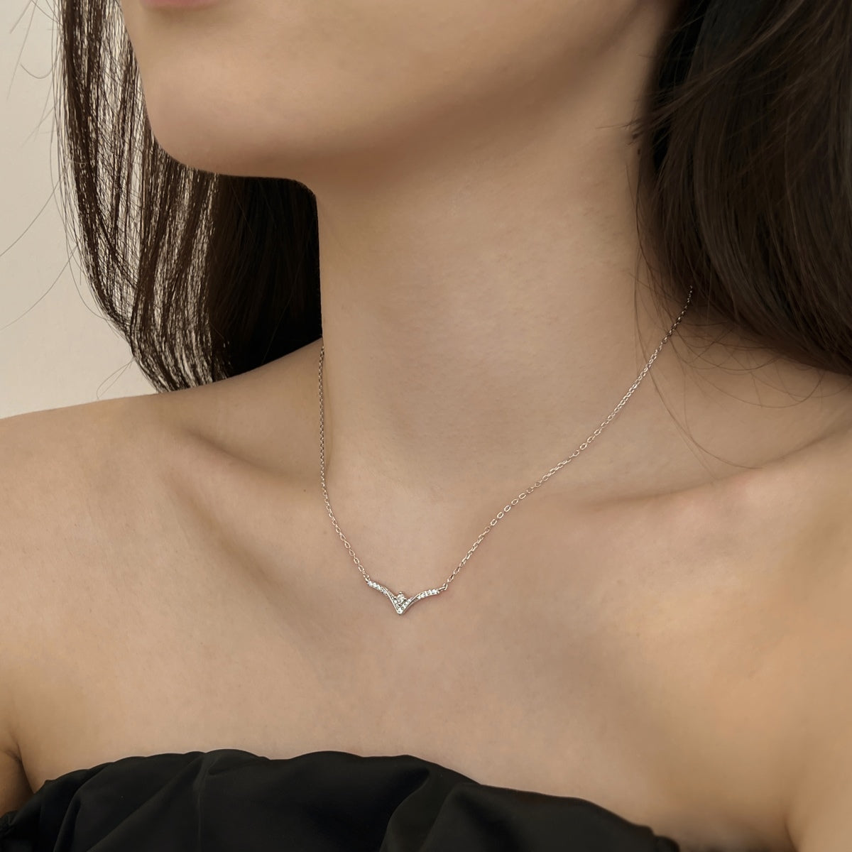 chevron pendant Necklace with a delicate design worn by a person against a neutral background