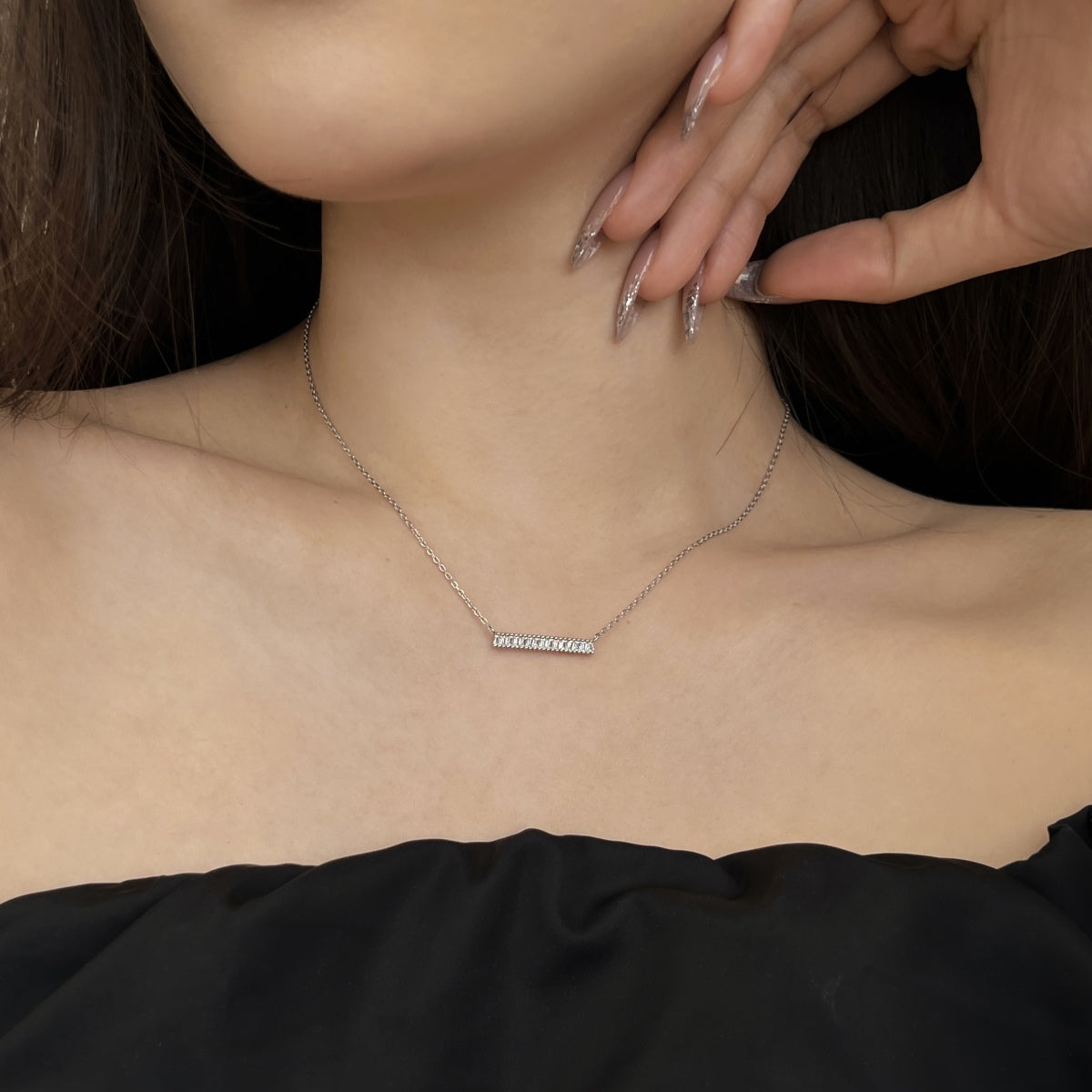 Necklace with a small rectangular pendant worn by a person