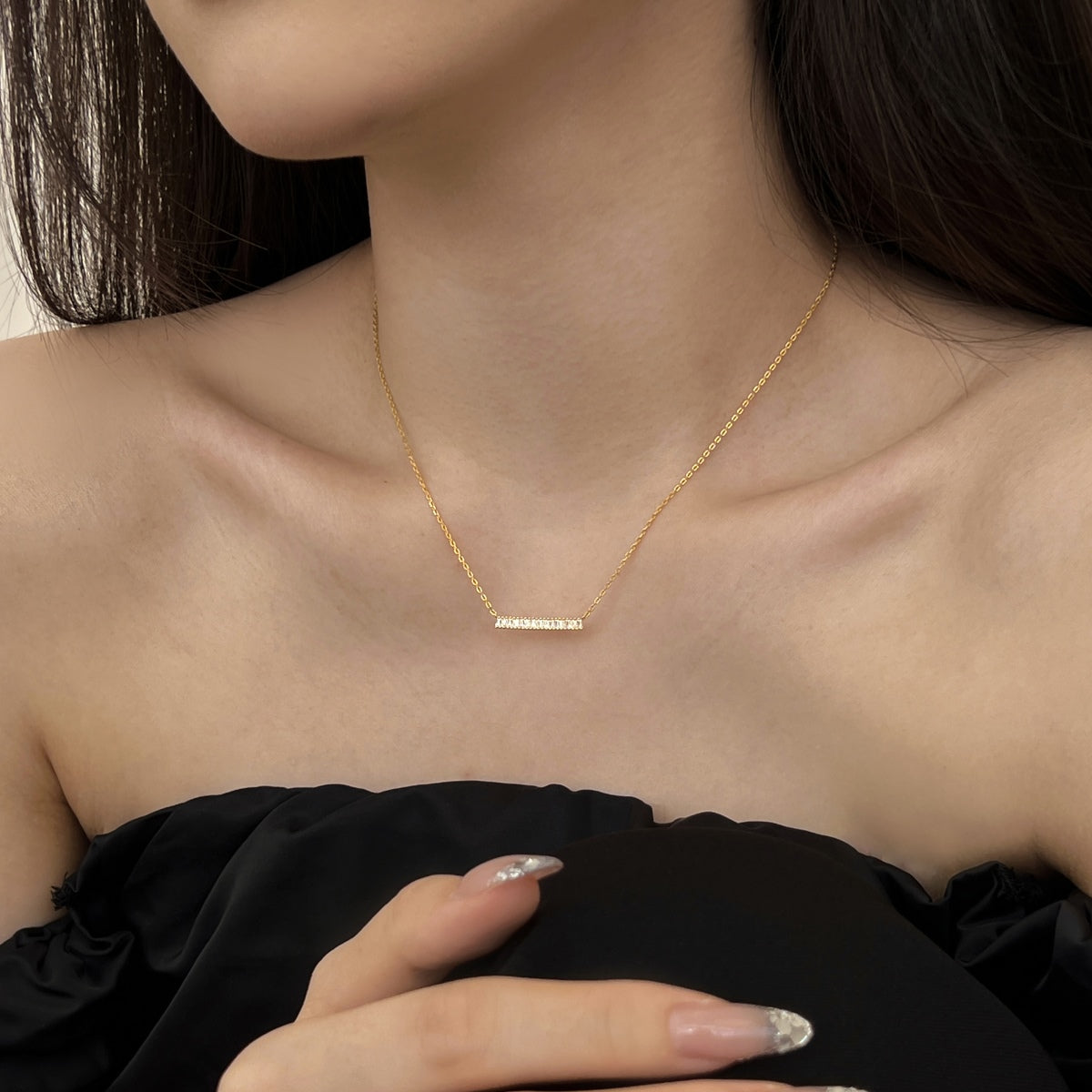 Gold necklace on a person wearing a black top