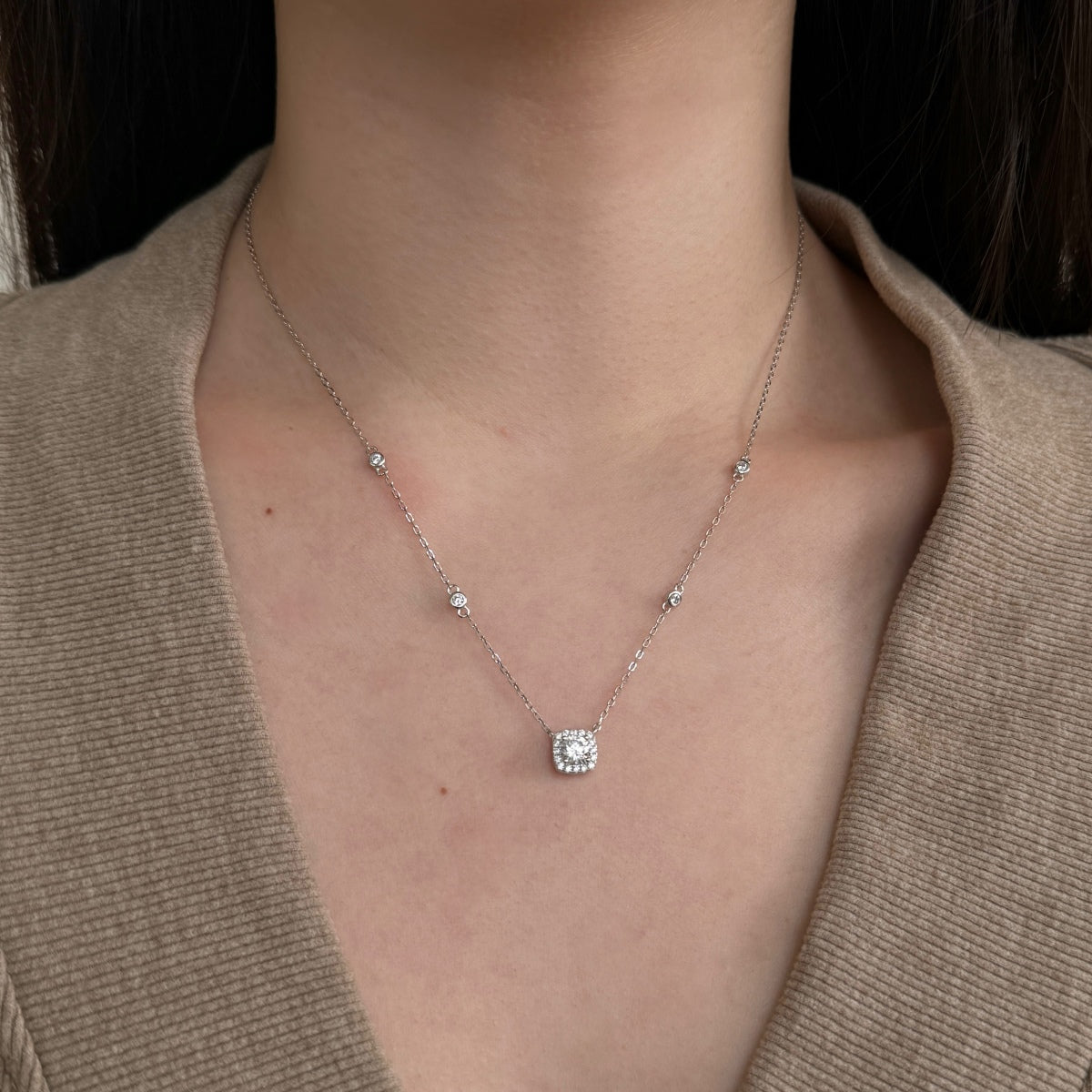Necklace with a pendant worn by a person, focusing on the jewelry against a neutral background.