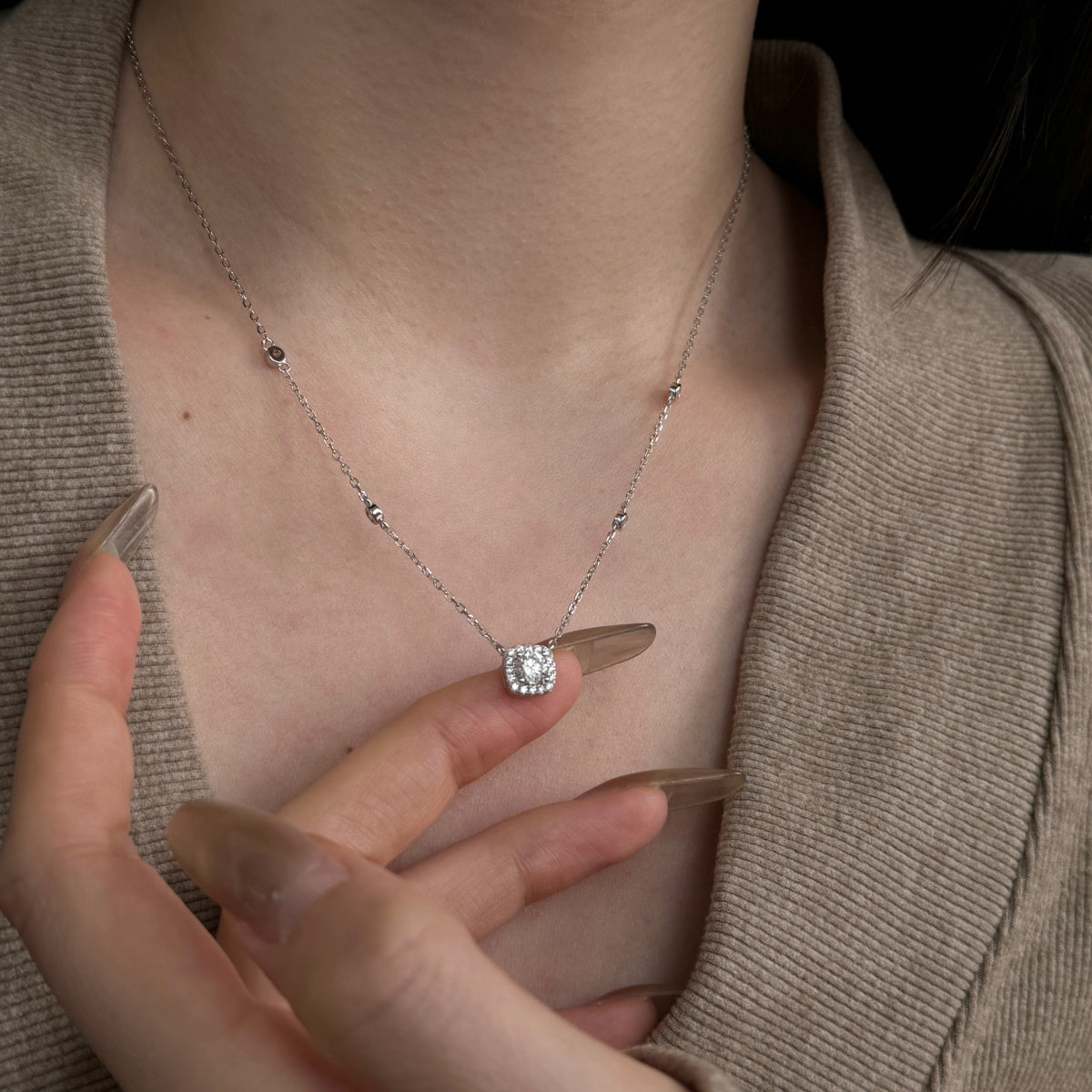 Necklace with a diamond pendant worn by a person, close-up shot.