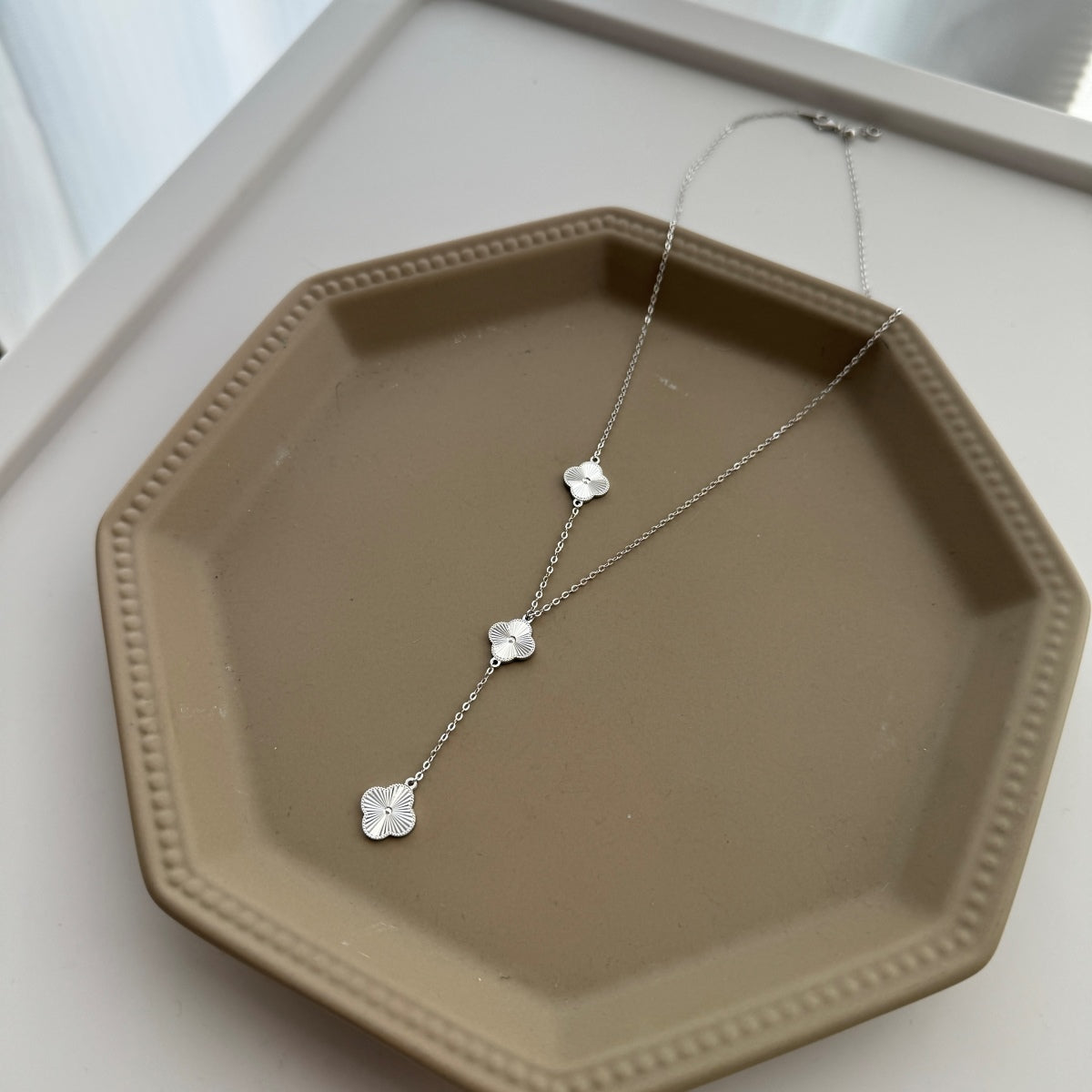 four leaf clover drop necklace on a jewelry plate 