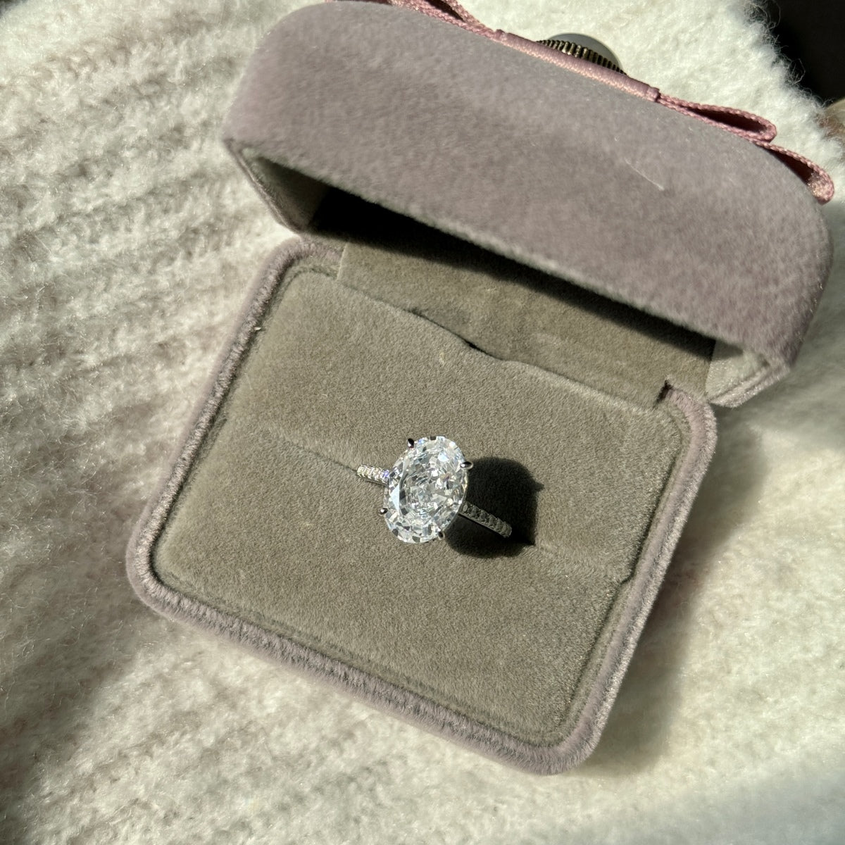 oval Diamond ring in a gray velvet box on a textured surface