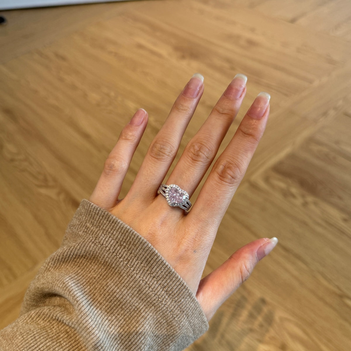 Hand wearing a ring on a wooden floor