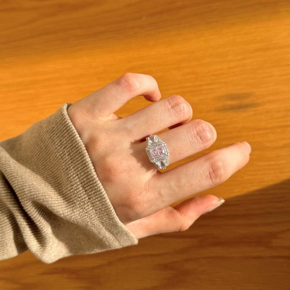 Hand wearing a ring with a wooden background
