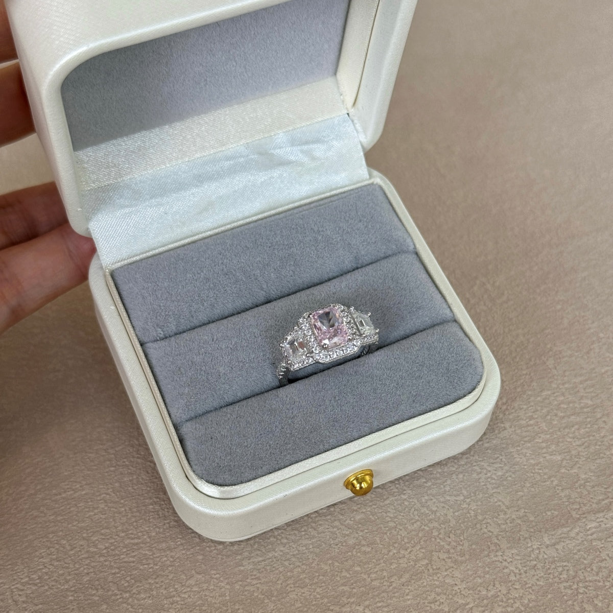 Diamond ring in a jewelry box on a beige surface