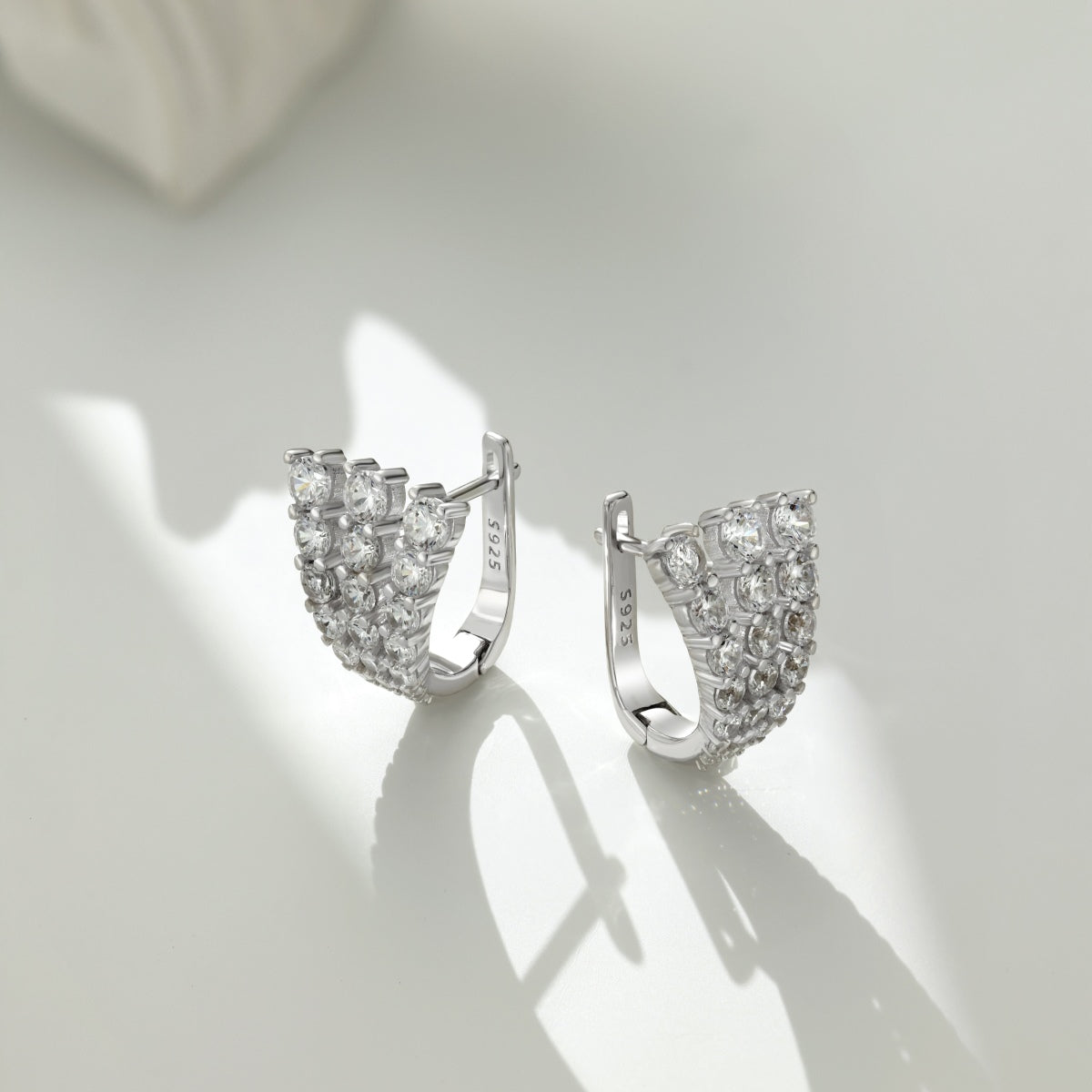 Pair of silver hoop earrings with clear gemstones on a light gray background