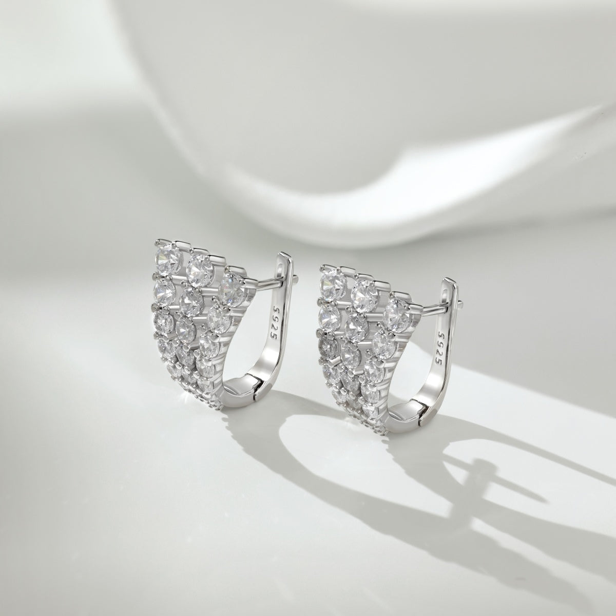 Silver hoop earrings with clear gemstones on a light gray background