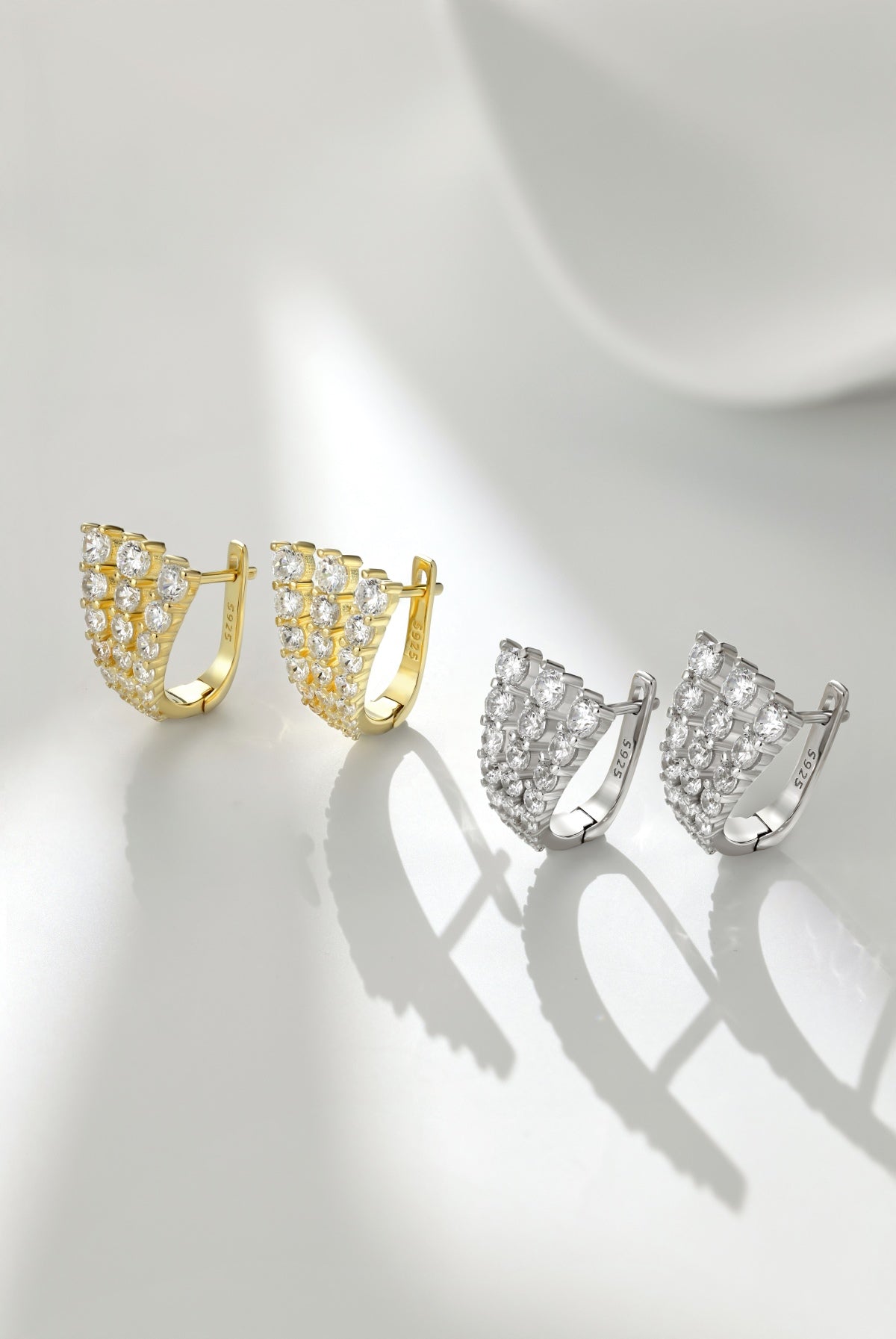 Pair of gold and silver hoop earrings on a light gray background