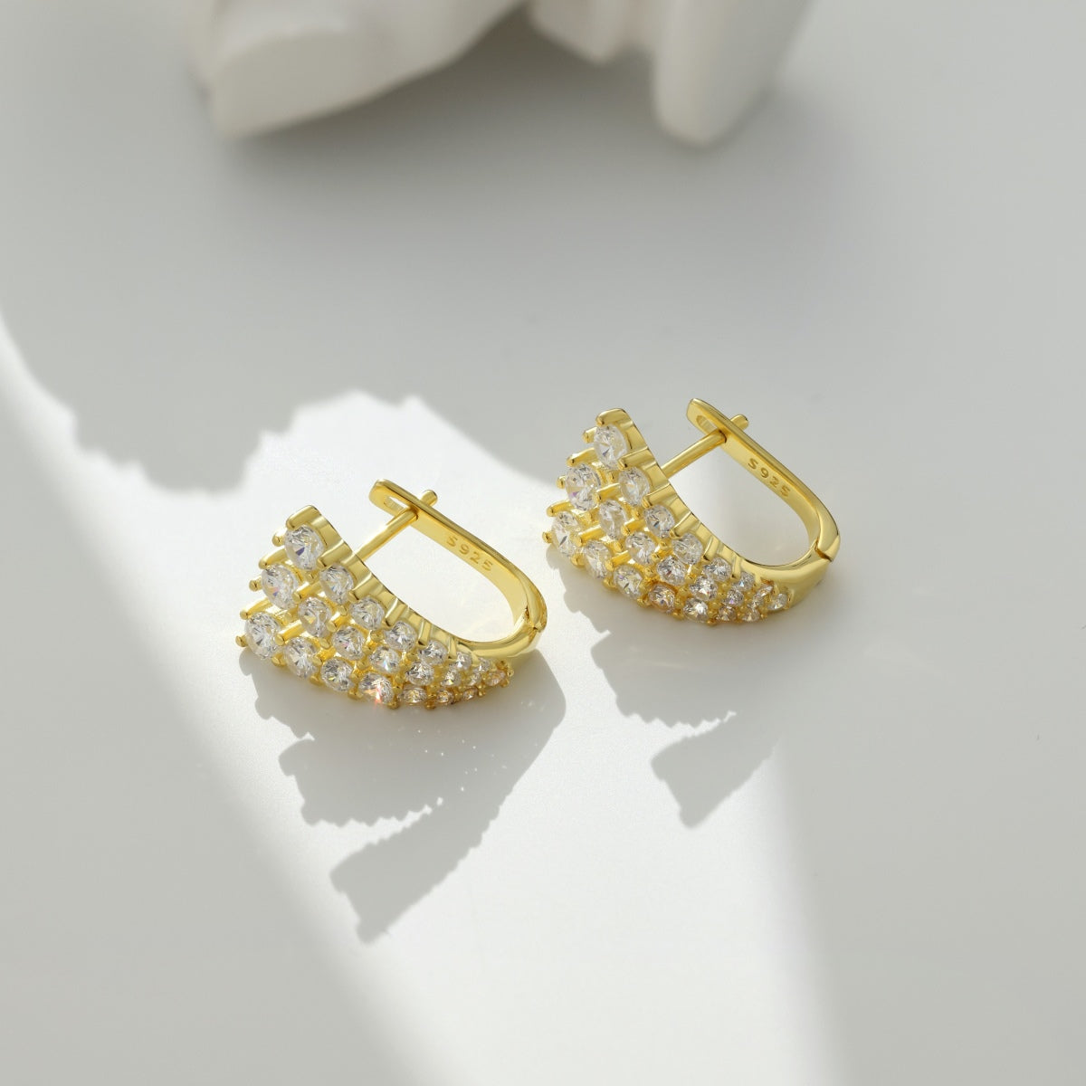 Gold hoop earrings with clear stones on a light background