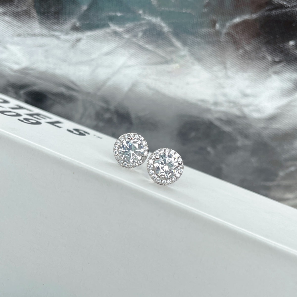 Timeless silver stud earrings with round center stone and micro pave halo