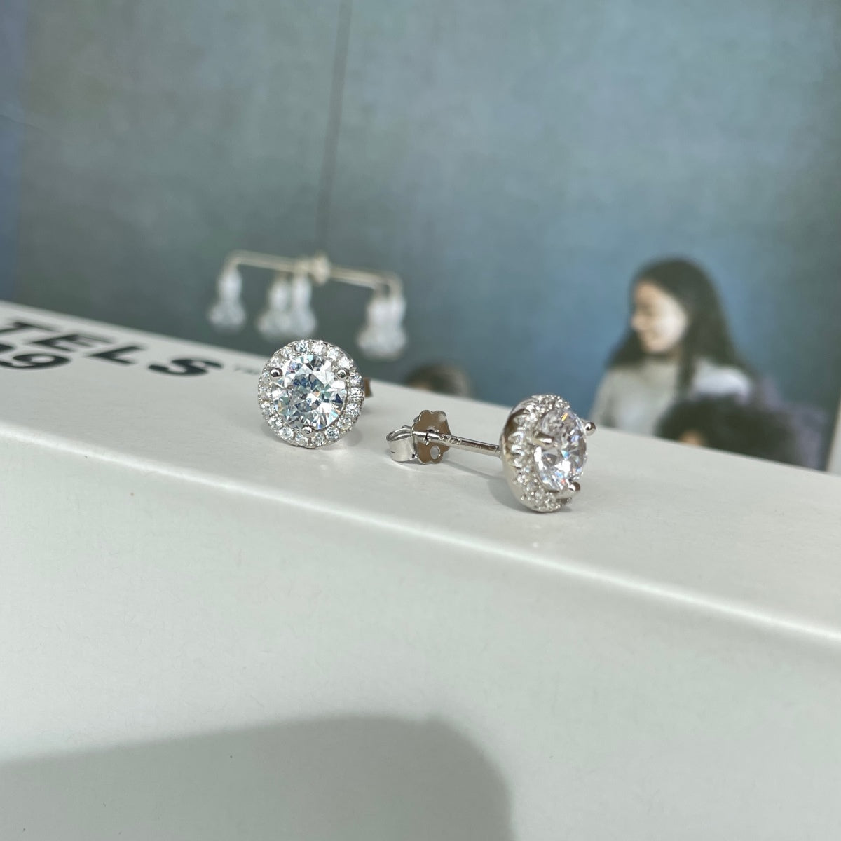 Close-up of sparkling round-cut zircon halo studs on white background