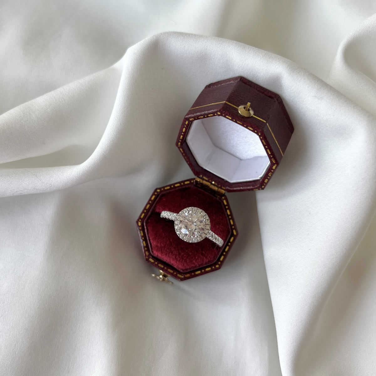 Diamond ring in a red jewelry box on white fabric