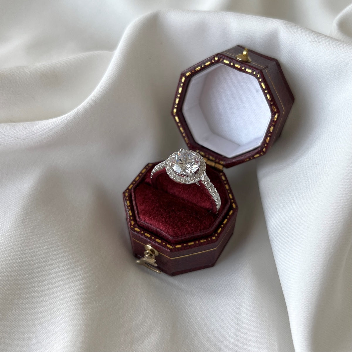 Diamond ring in an open red jewelry box on a white fabric background