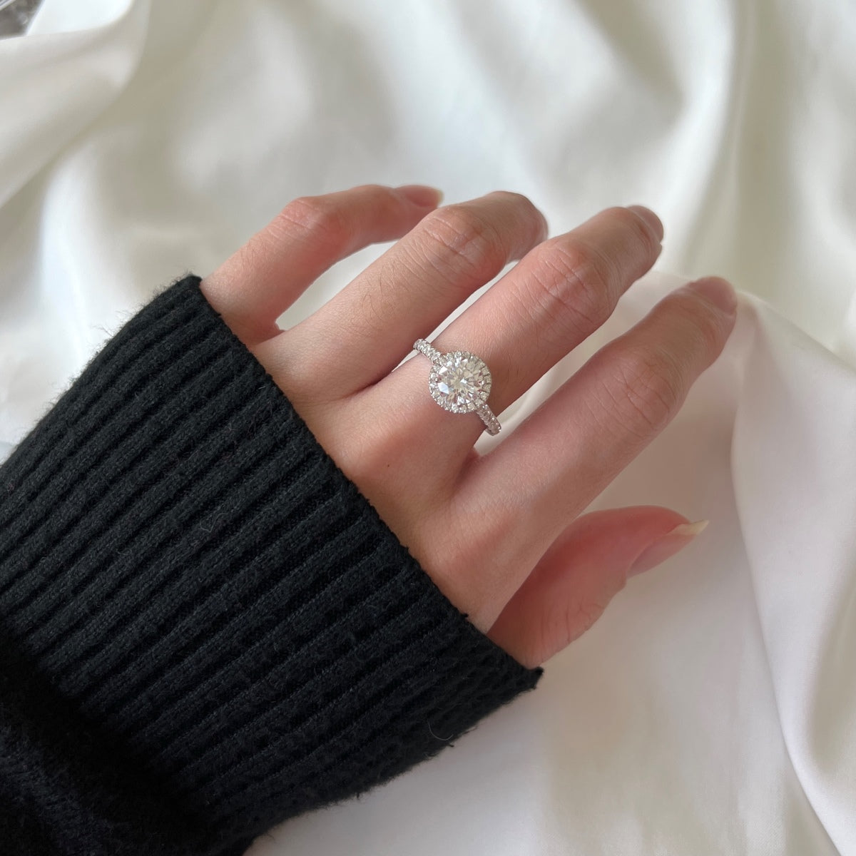 Close-up of a hand wearing a diamond ring on a white background
