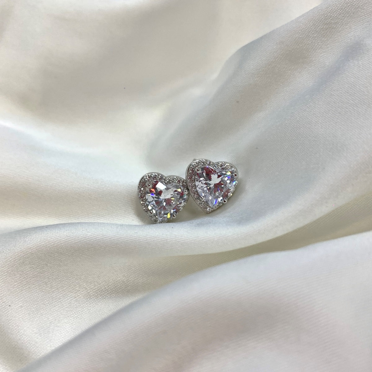 Heart-shaped stud earrings on a satin surface