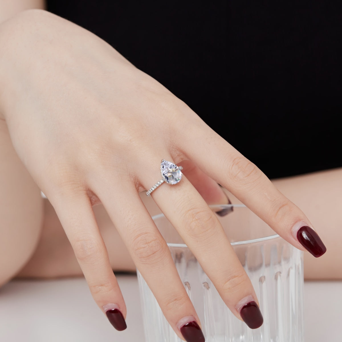 model wearing teardrop diamond ring on white background