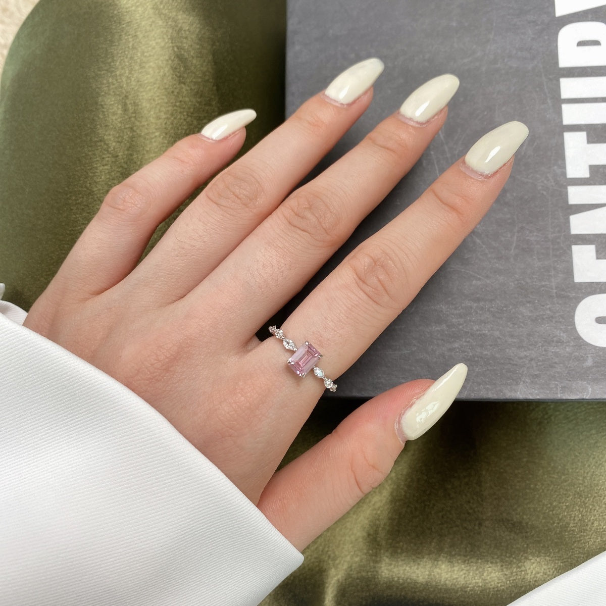 Hand wearing a pink gemstone ring with a neutral background