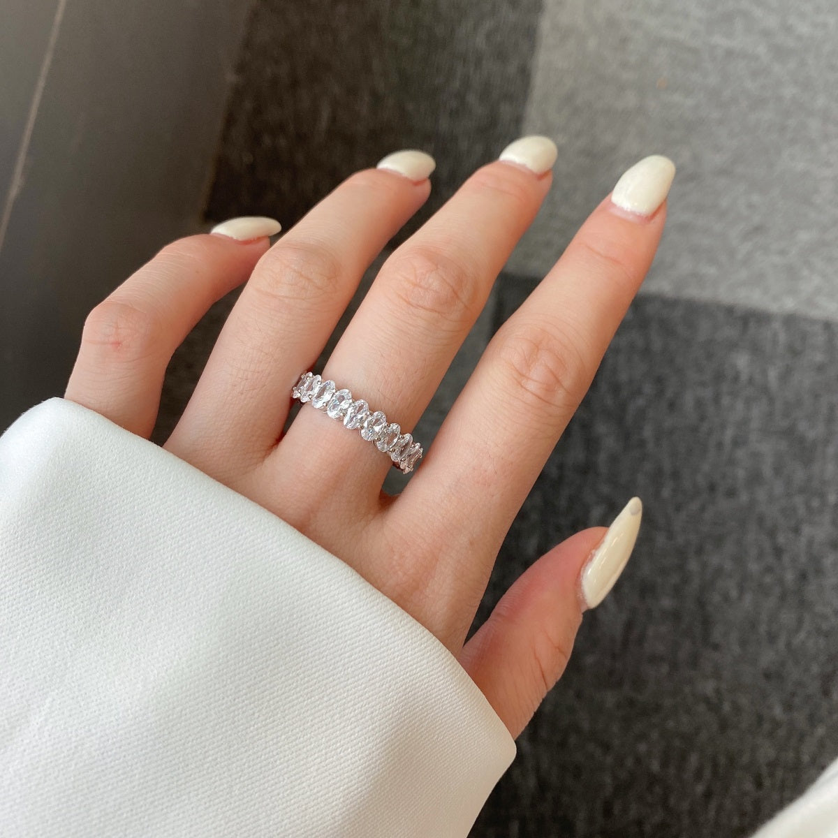 Hand wearing a diamond ring with a neutral background