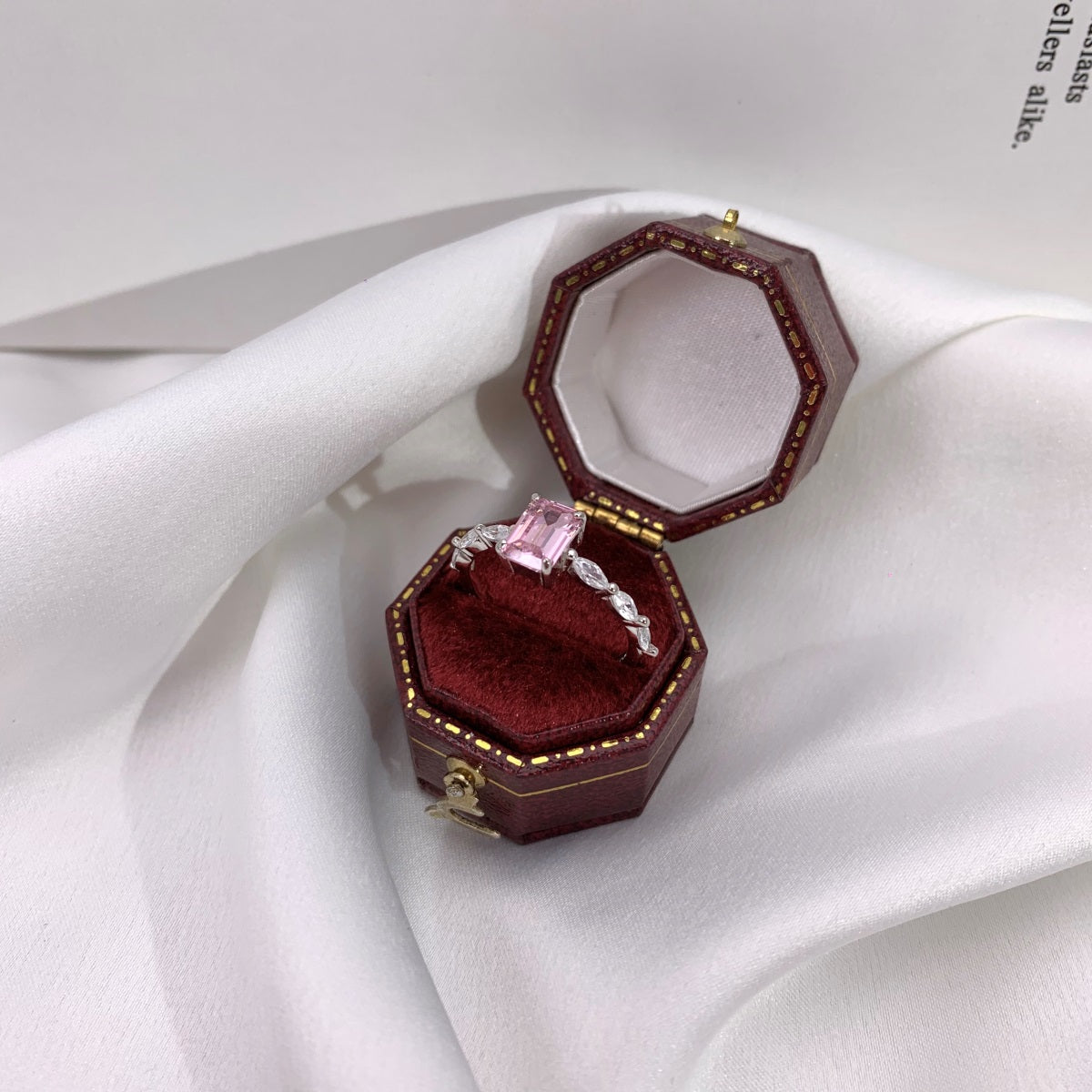 Open red jewelry box with a ring on a white fabric background