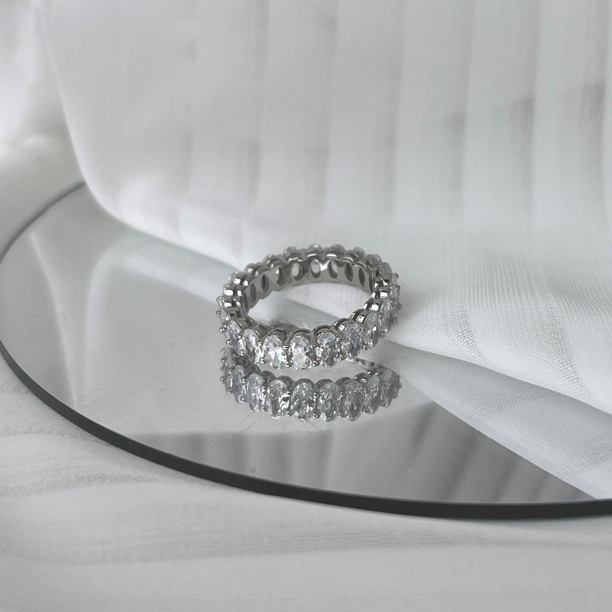 Two silver rings with gemstones on a white fabric background