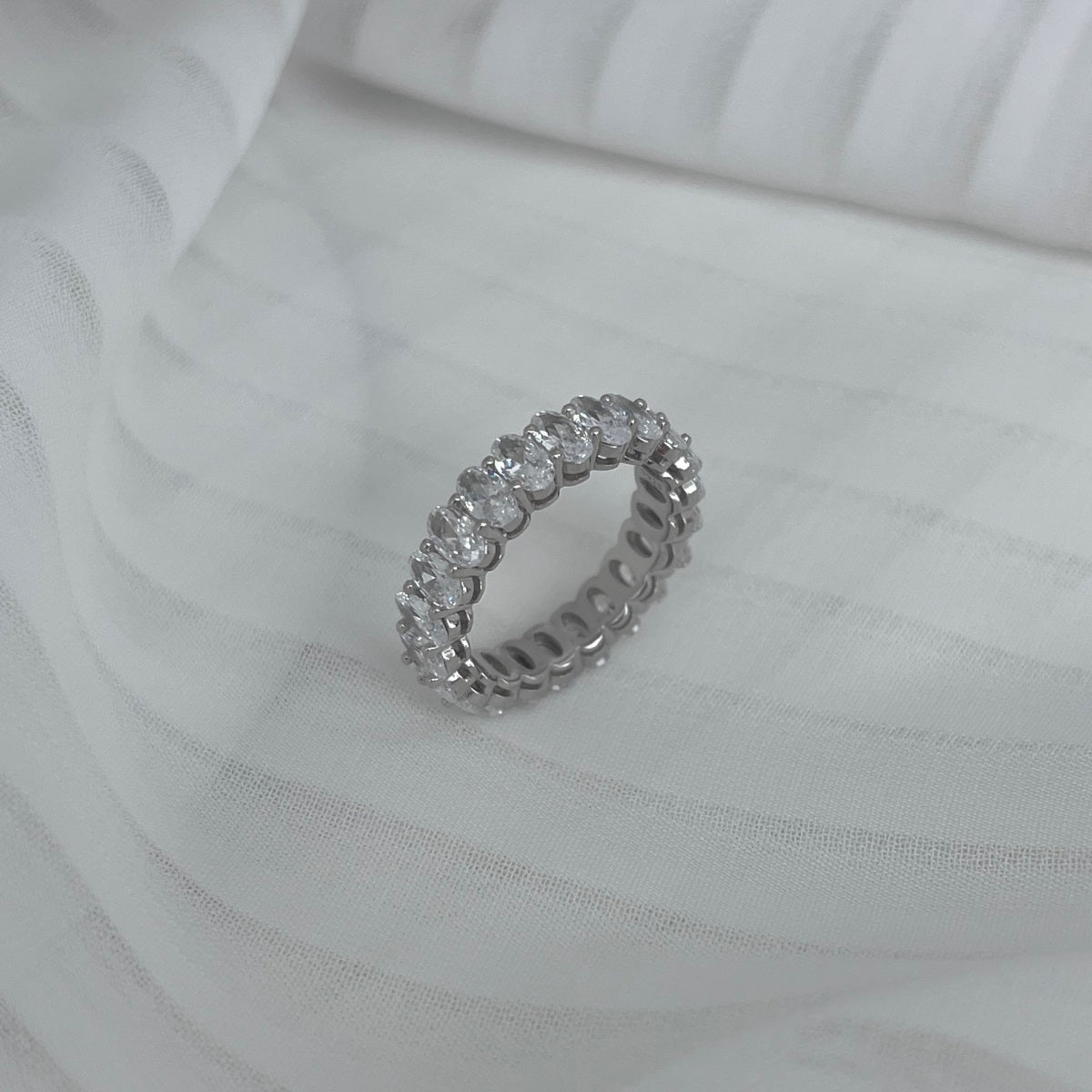 Silver ring with diamonds on a white fabric background