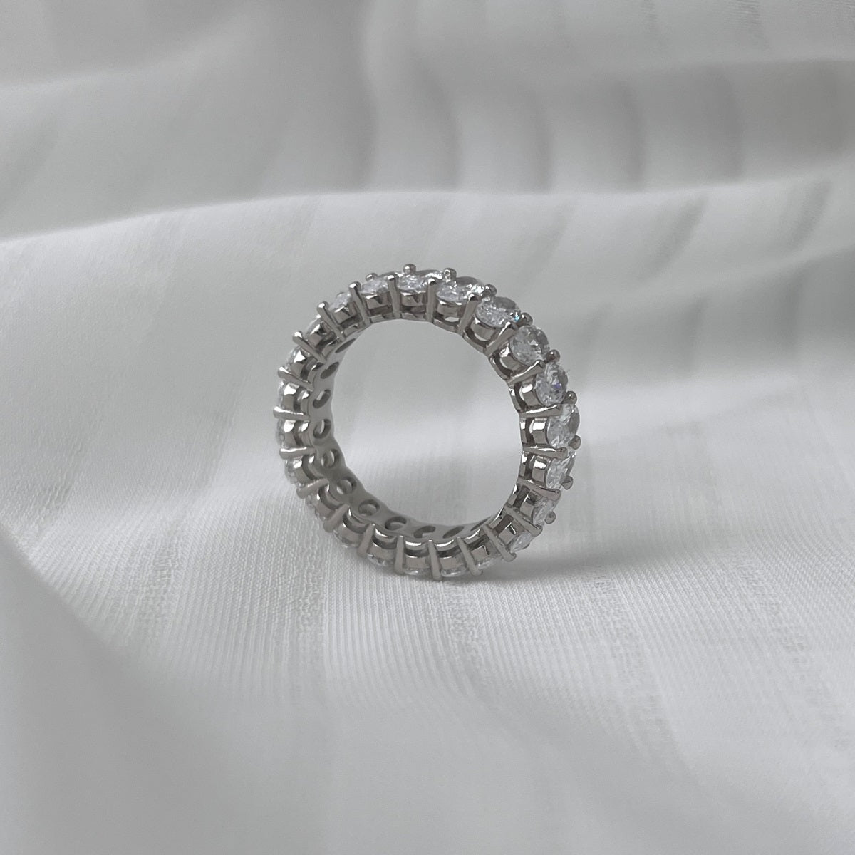 Silver ring with diamonds on a white fabric background