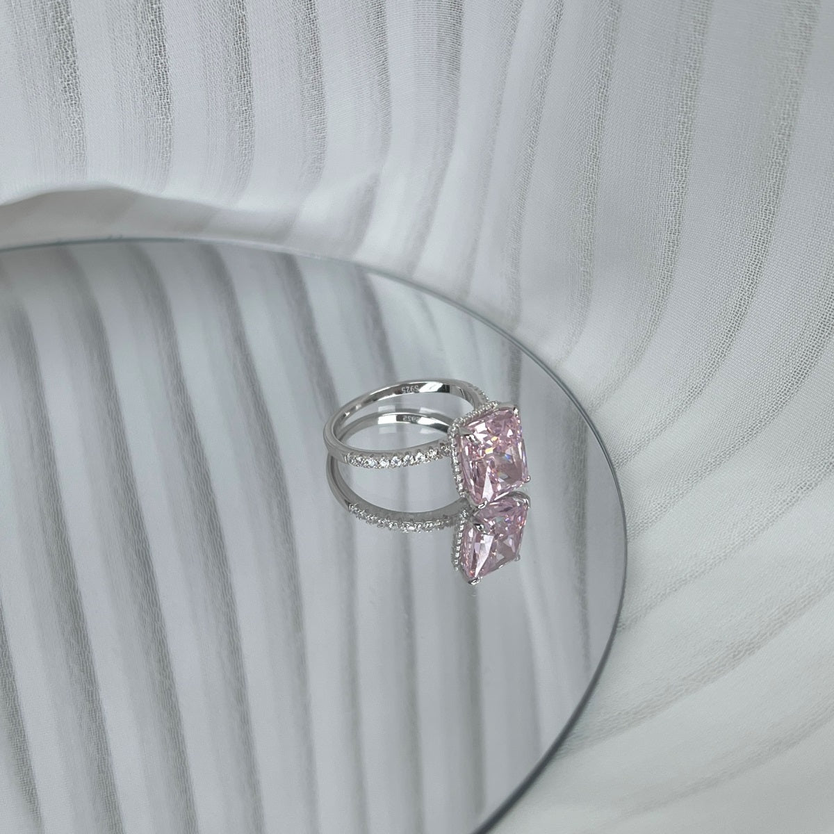 Silver ring with a pink gemstone on a textured white background